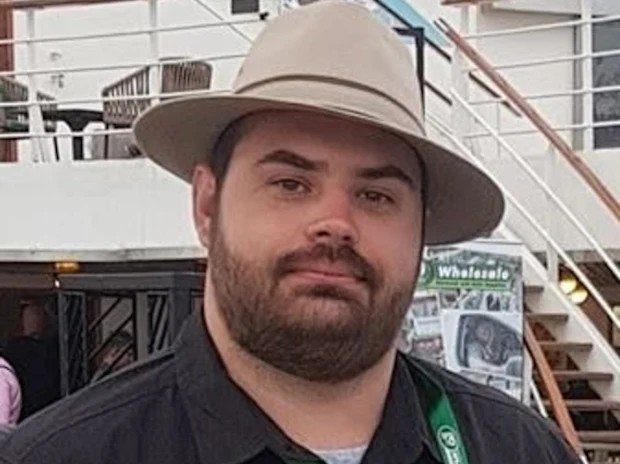 Joshua MacDonald, a bearded man in a wide-brimmed hat and dark shirt, photographed on the deck of a boat