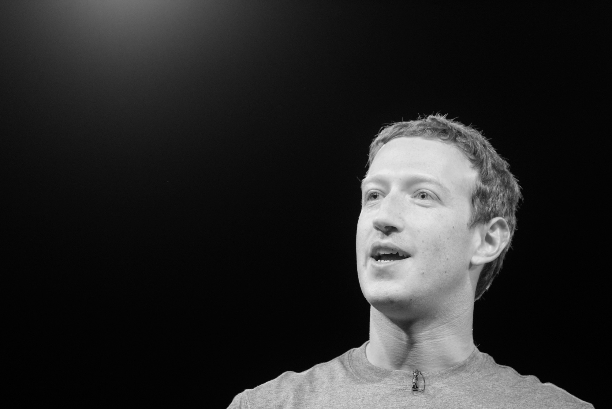 Mark Zuckerberg photographed in black and white, in profile, at a conference